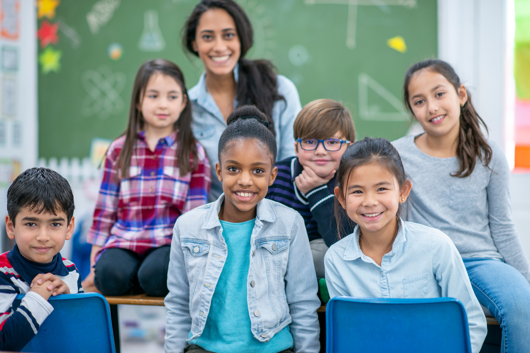 a group of individuals sitting on chairs in front of a blackboard